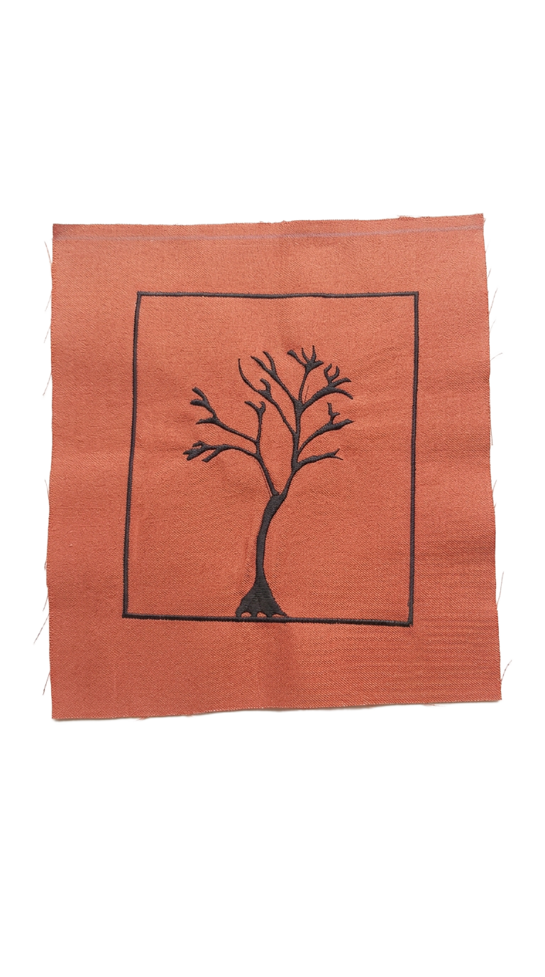 Black tree motif embroidered on coral fabric